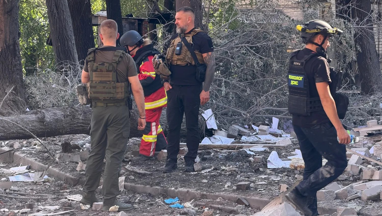 Рятувальники в захисному спорядженні обстежують місце удару серед уламків і повалених дерев у Запоріжжі