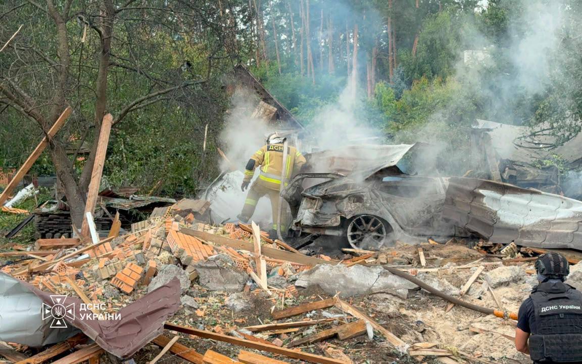 Рятувальники працюють біля розбитого автомобіля на місці ракетного удару в Київській області, 24 липня 2026 року