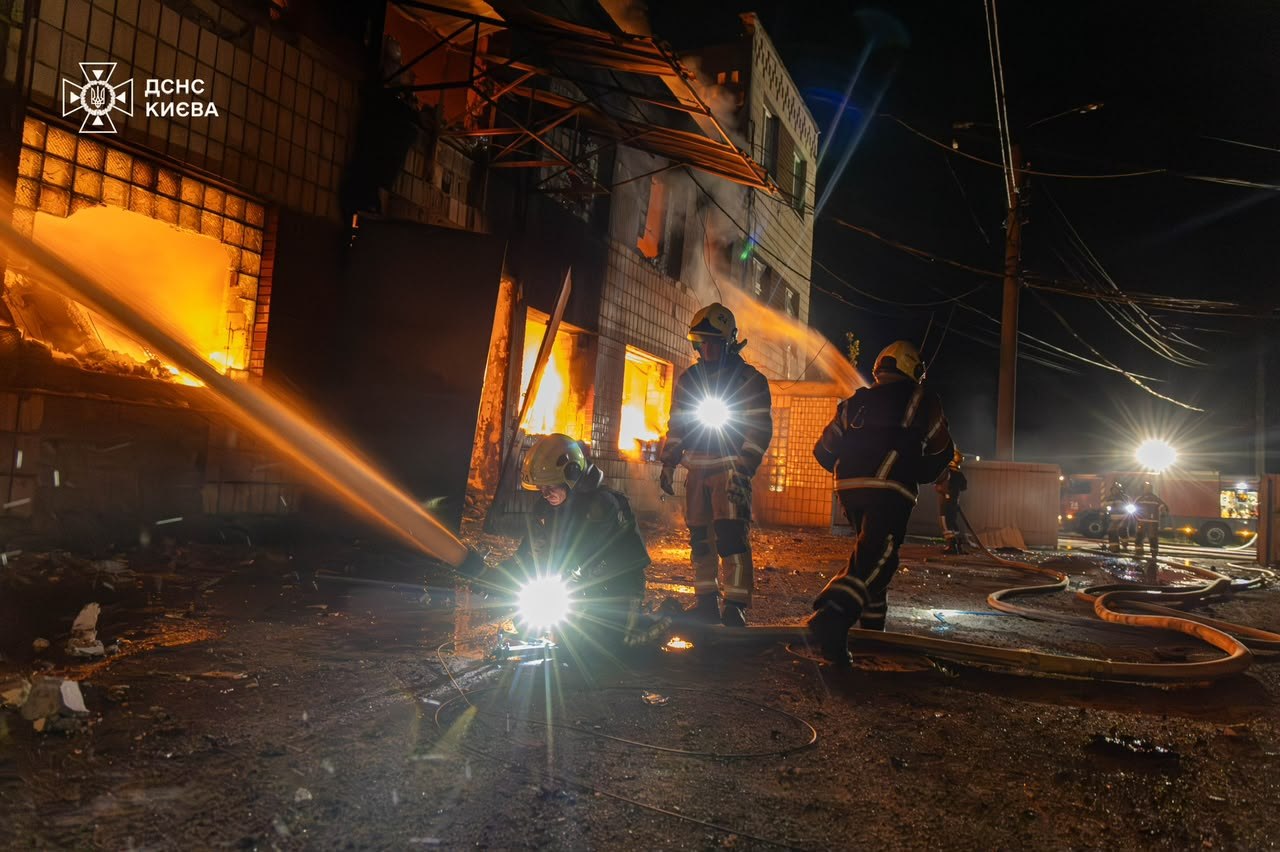 Рятувальник гасить пожежу на складі в Києві після балістичного удару