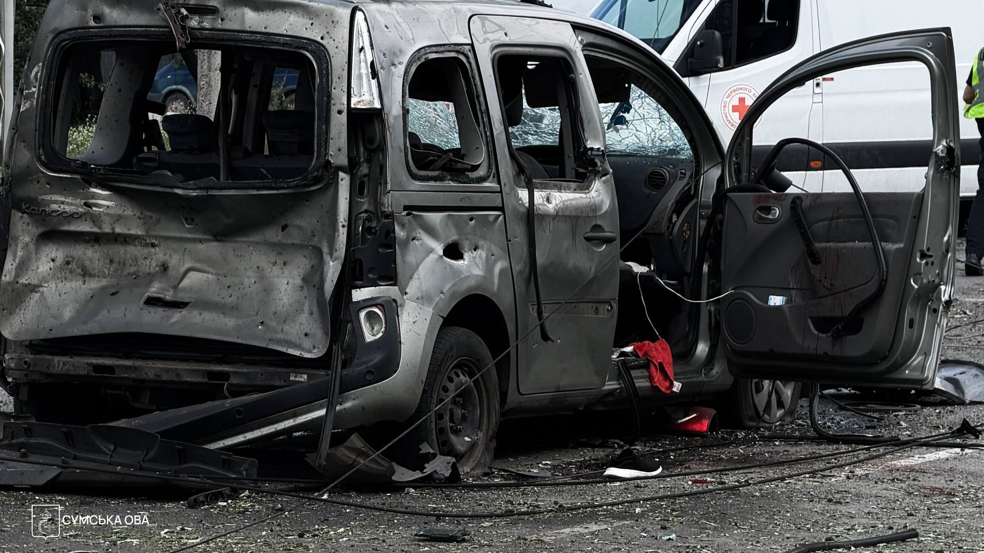 Понівечений автомобіль з розбитими вікнами біля карети швидкої допомоги на місці удару в Сумах