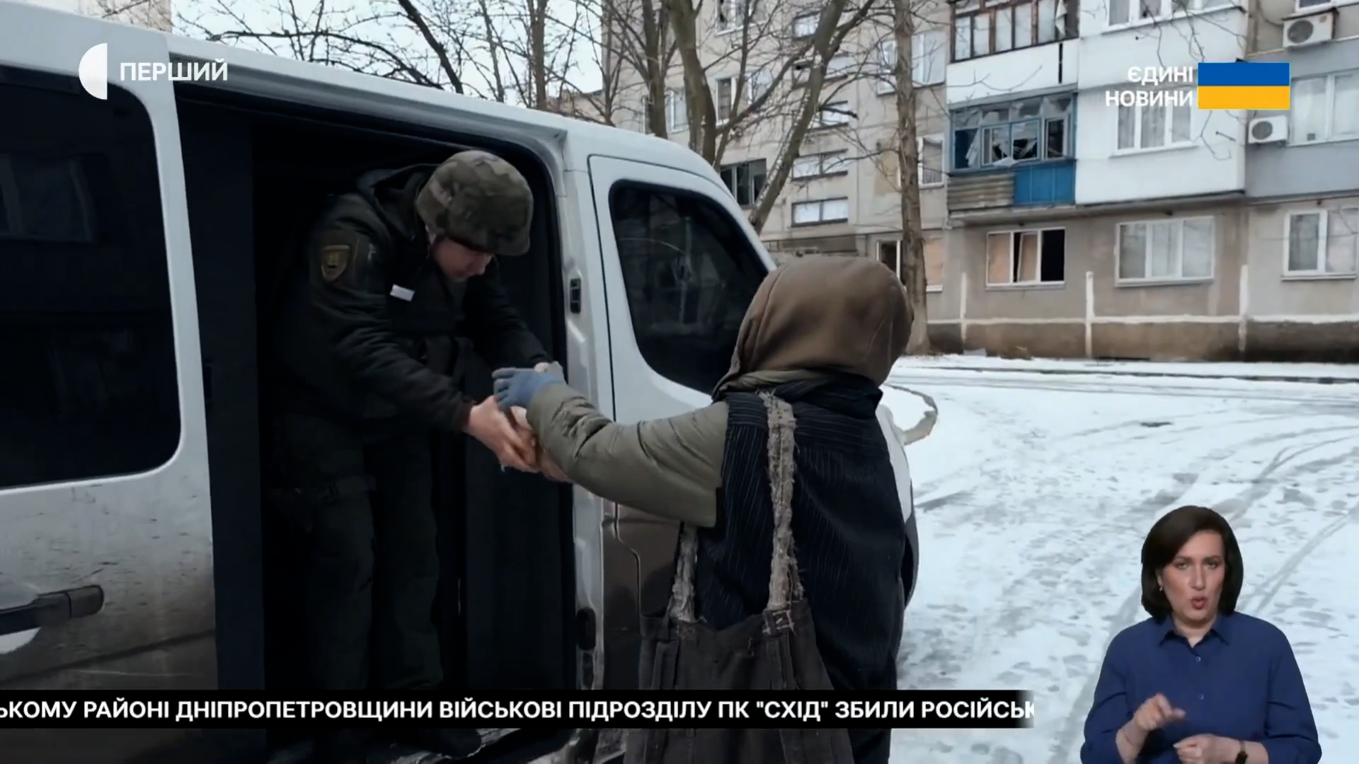Поліцейський допомагає жінці сісти в евакуаційний мікроавтобус біля пошкодженого будинку