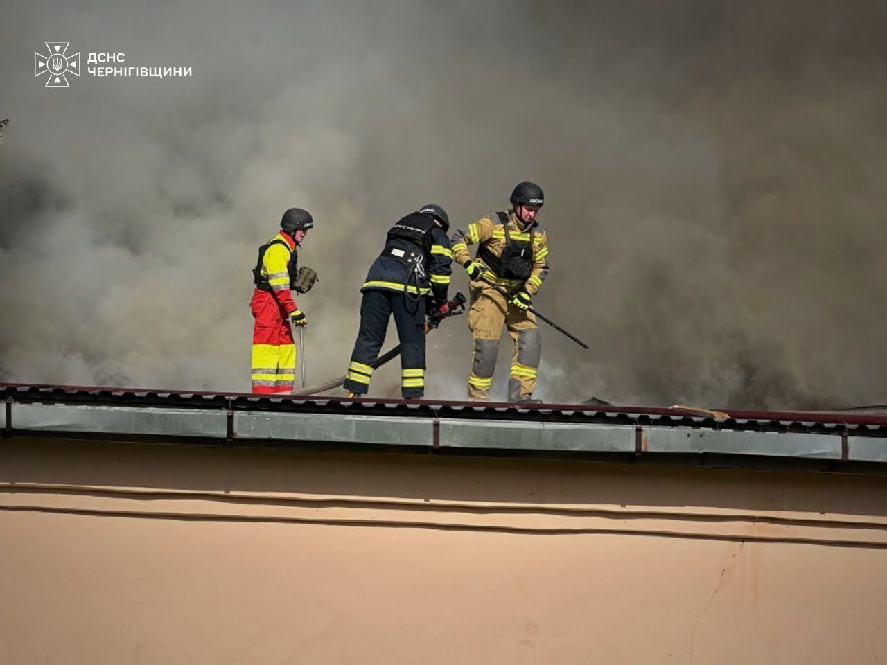 Пожежники на даху будівлі гасять масштабну пожежу після удару по супермаркету в Чернігові