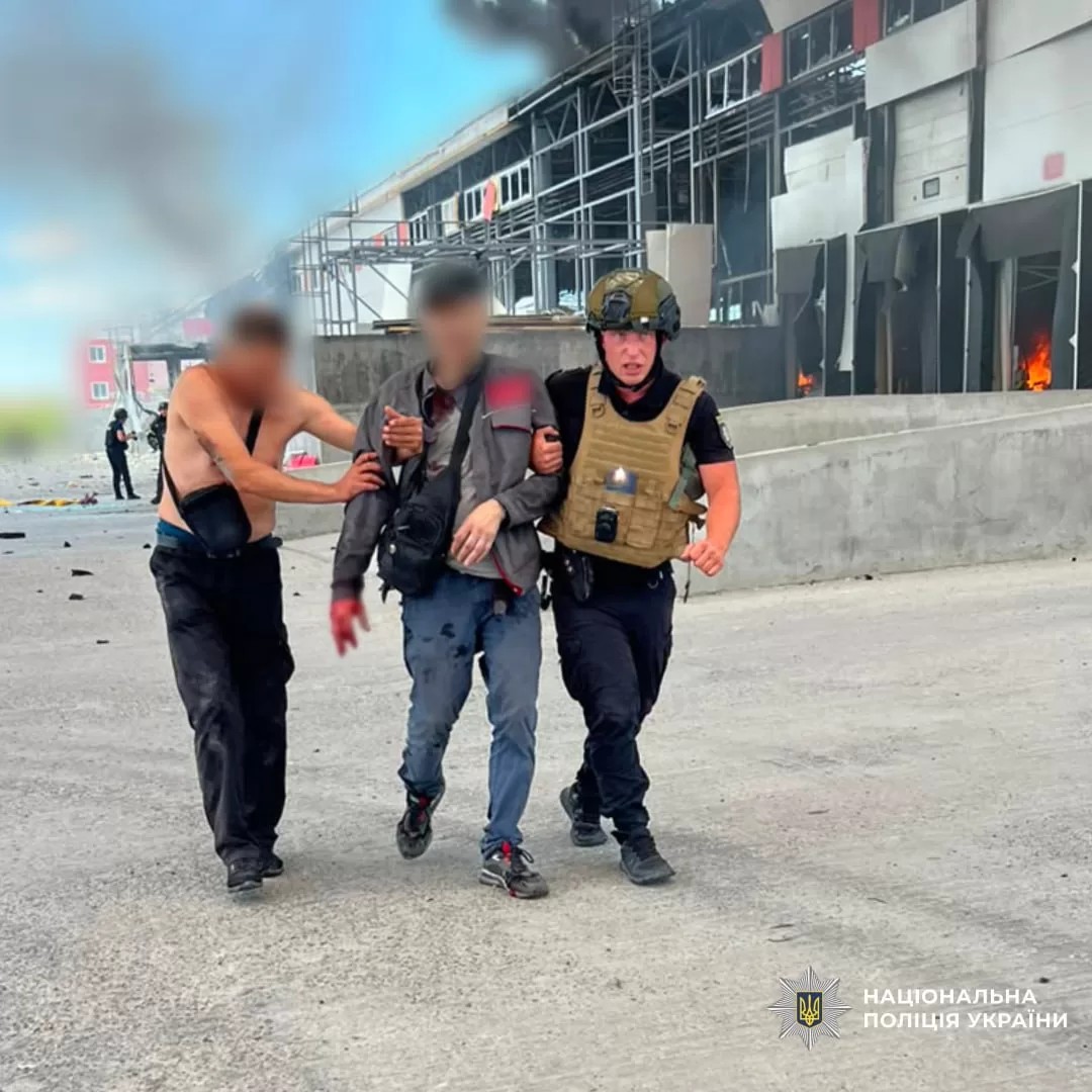 Поліцейський та цивільний виводять пораненого чоловіка з місця удару