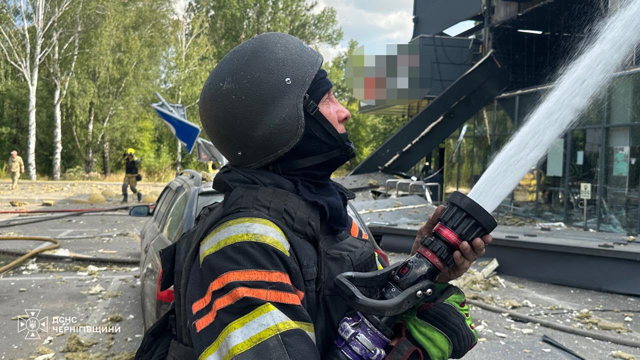 Рятувальник гасить пожежу на місці удару дрона по супермаркету в Чернігові