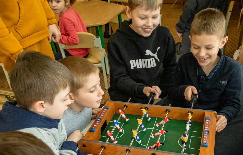 Children playing foosball together at a Save Ukraine reception center