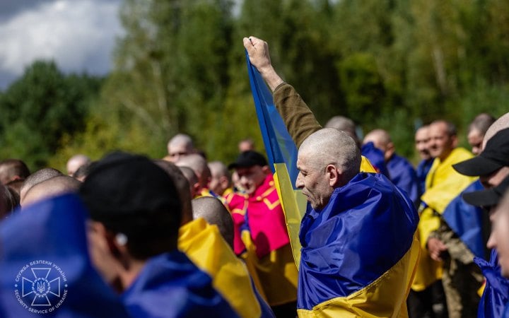 Released Ukrainian service members with national flags over their shoulders straight after the exchange