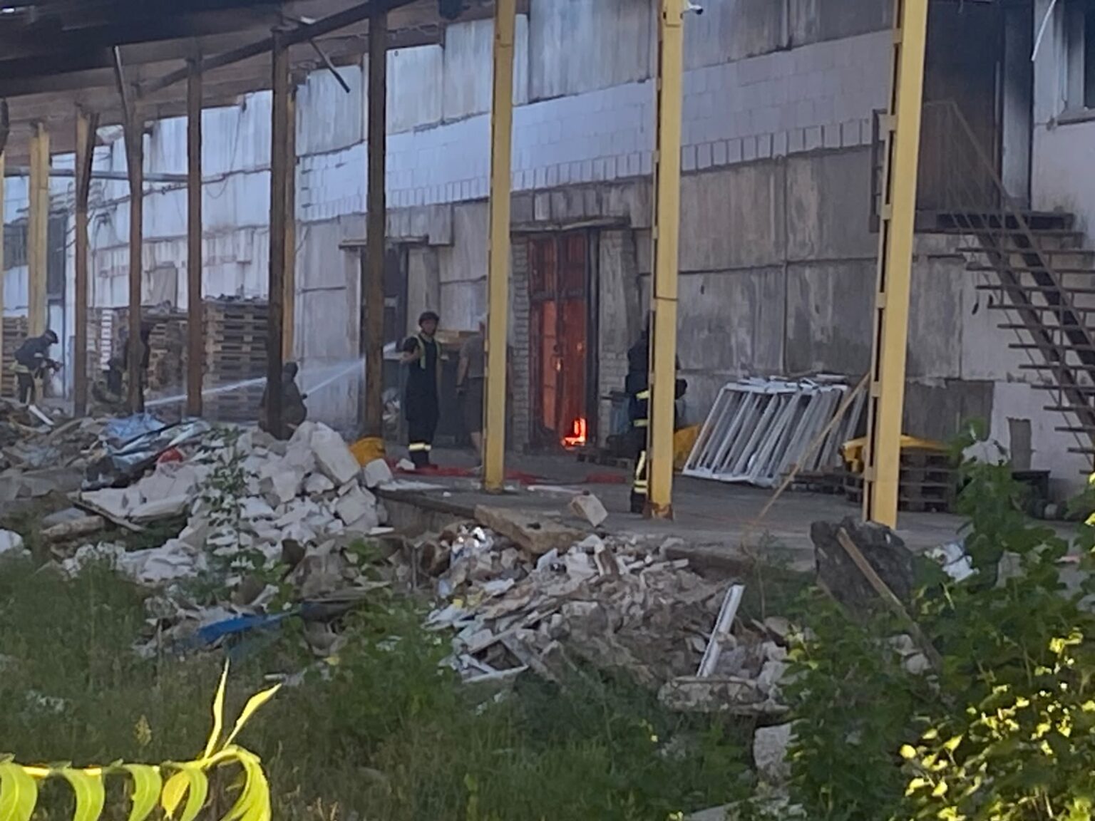 Рятувальники працюють біля пошкодженого складського приміщення, видно обвалений дах і завали будівельного сміття