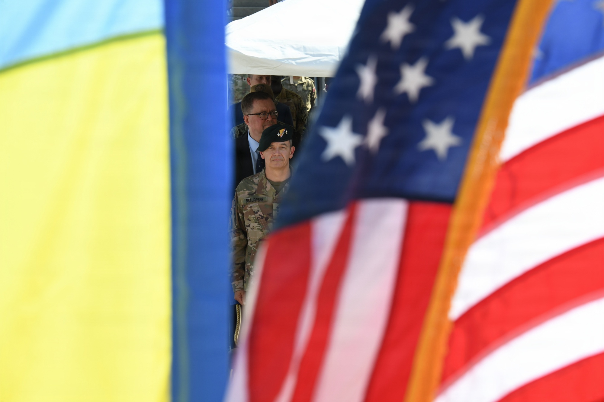 Генерал-лейтенант Гійом Н. Боппер прибуває на церемонію між прапорами України та США