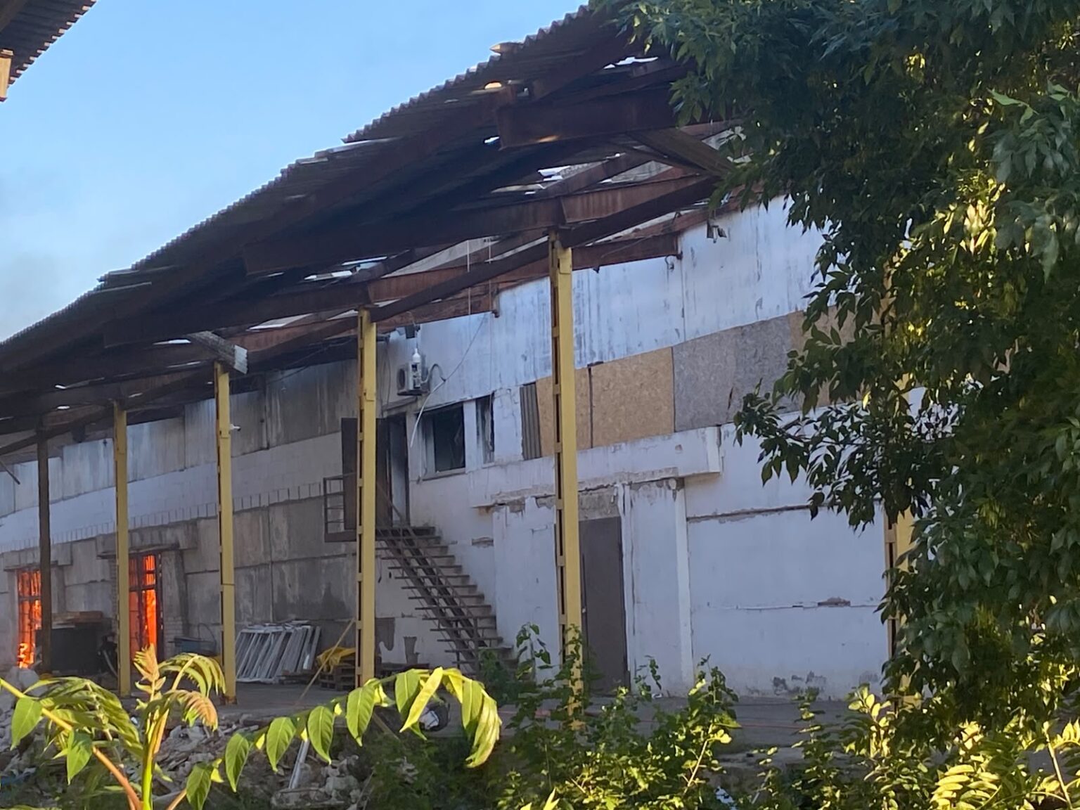 Пошкоджена будівля складу вдень після пожежі: обвалений дах, обгорілі конструкції, завали навколо