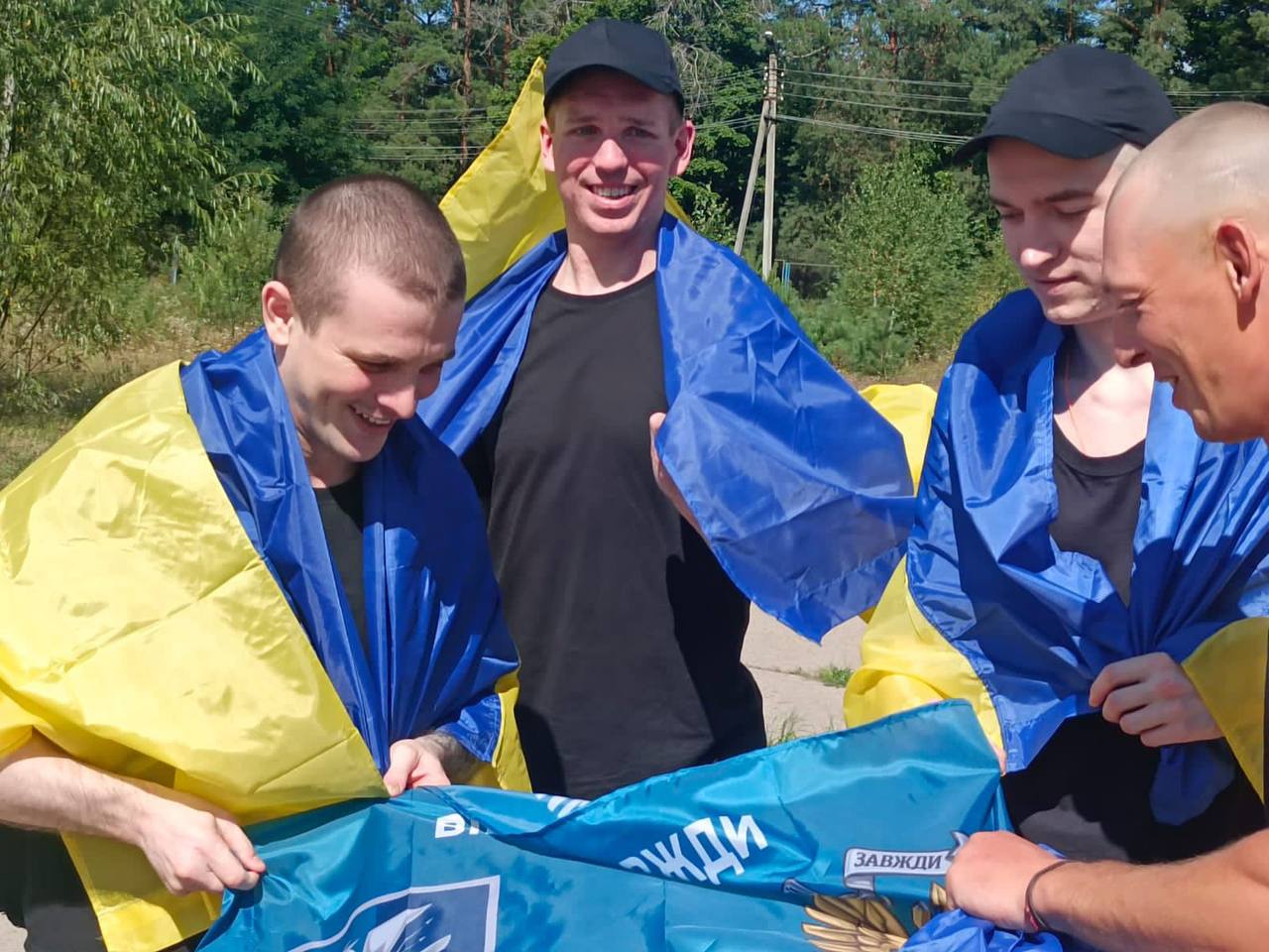 Звільнені українці, загорнуті у синьо-жовті прапори, святкують повернення додому