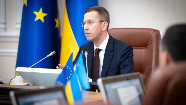 Прем'єр-міністр України виступає на тлі прапорів України та ЄС