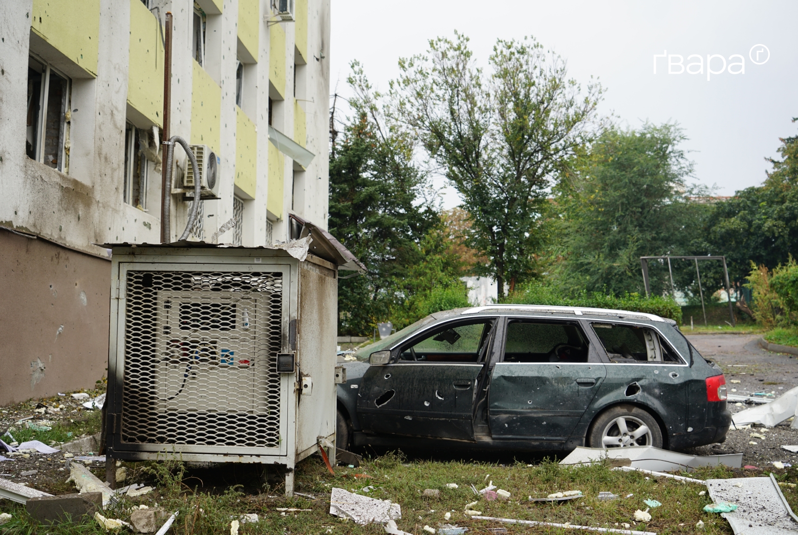 A car and building damaged by shrapnel after a strike on Izyum