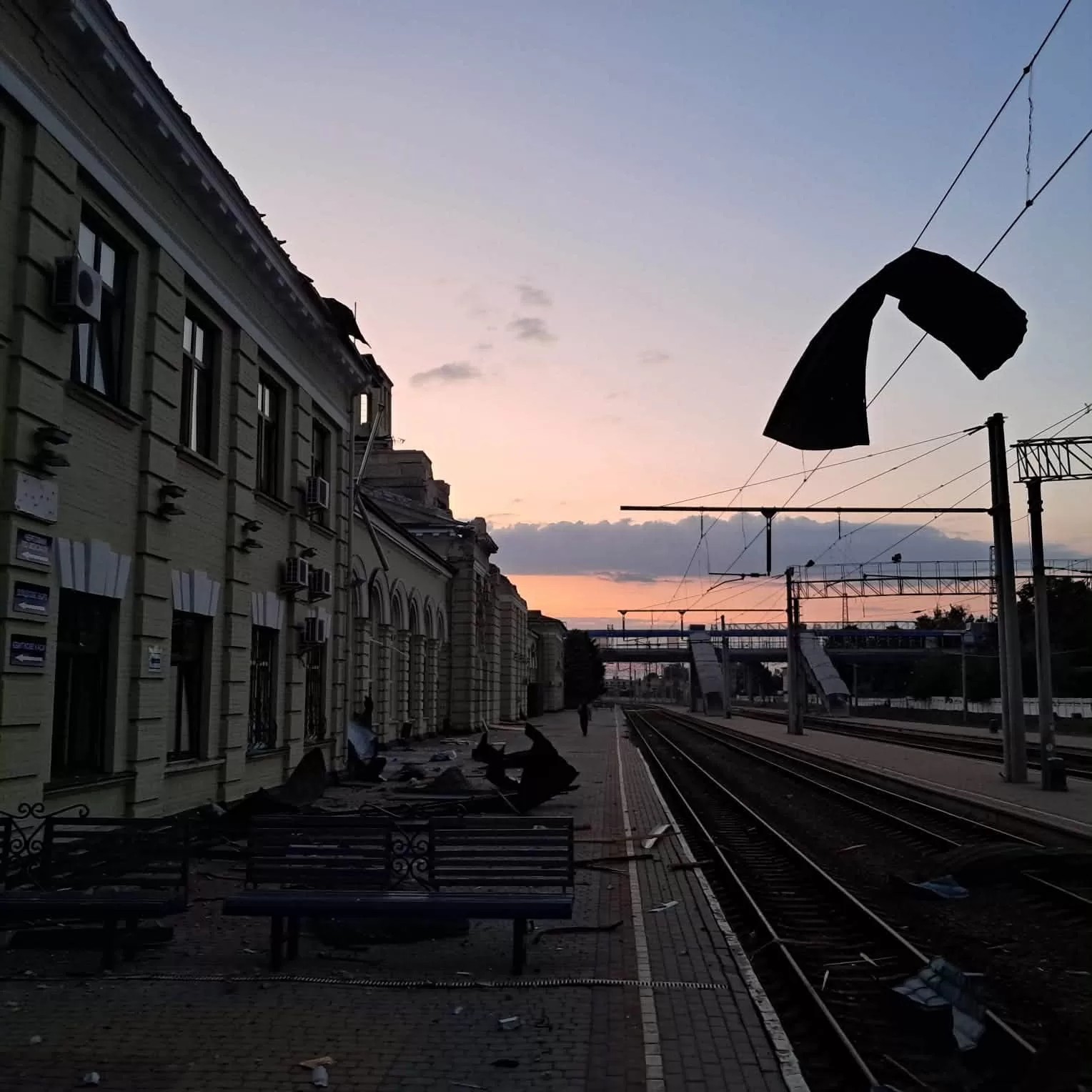 Damaged overhead power lines and debris on the platform at Lozova train station at dawn