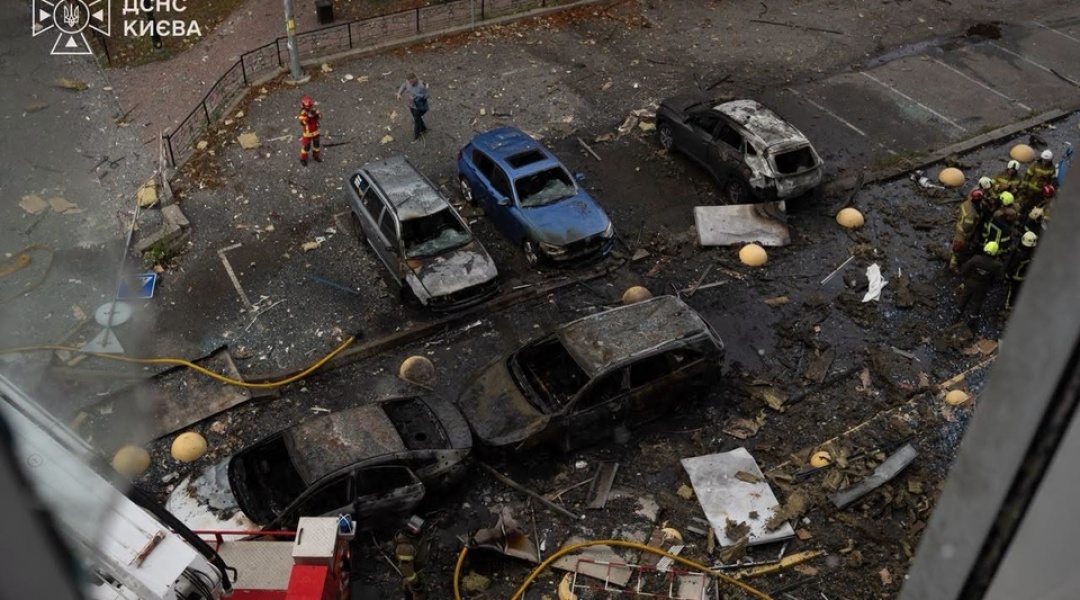 Burned-out cars in a courtyard and Kyiv emergency crews at the scene of the attack