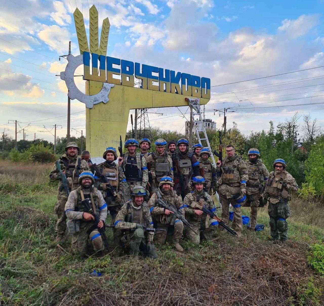 Військові тероборони біля в'їзного знаку в звільненому Шевченковому, перефарбованого з кольорів прапора Росії на українські, ілюстративне фото 2022 року