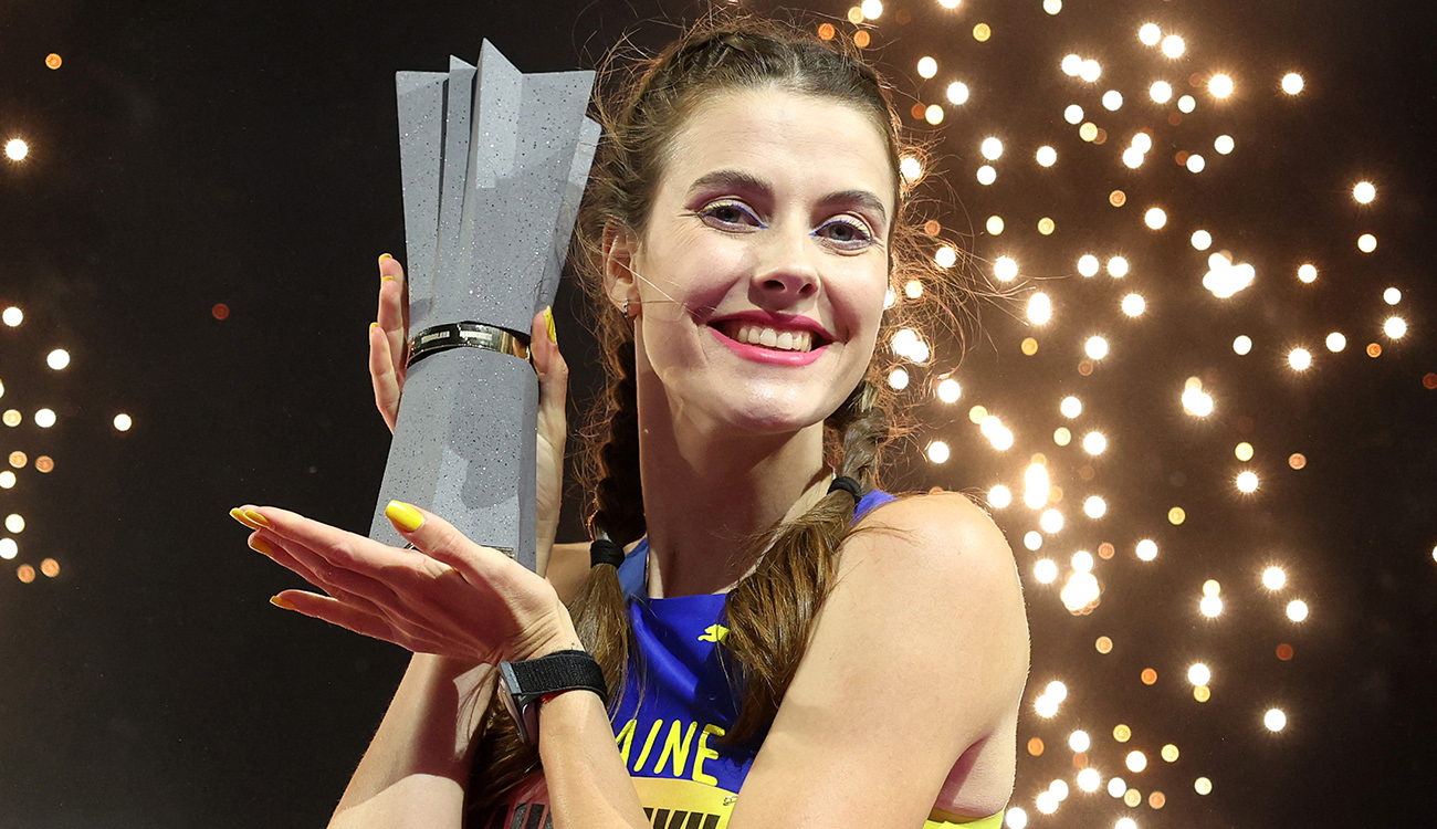 Yaroslava Mahuchikh holds her trophy as fireworks light up the stadium