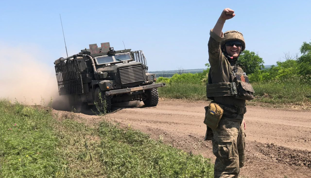 Український військовий подає сигнал біля бронетехніки, що рухається до позицій