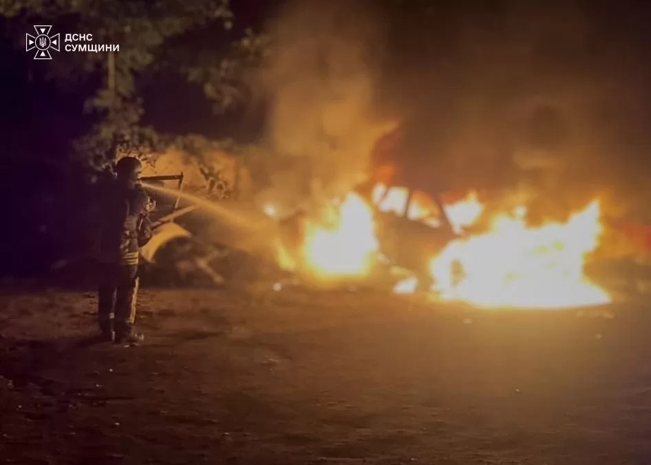 Firefighters extinguish a burning vehicle after a Russian drone strike in Sumy