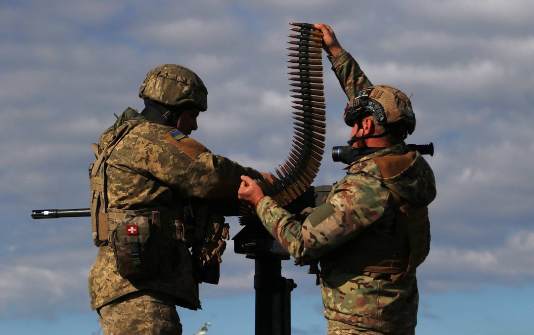 Українські воїни споряджають стрічку для кулемета на позиції