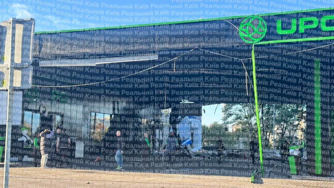 A damaged canopy at a Kyiv gas station after a drone strike, as workers survey the scene