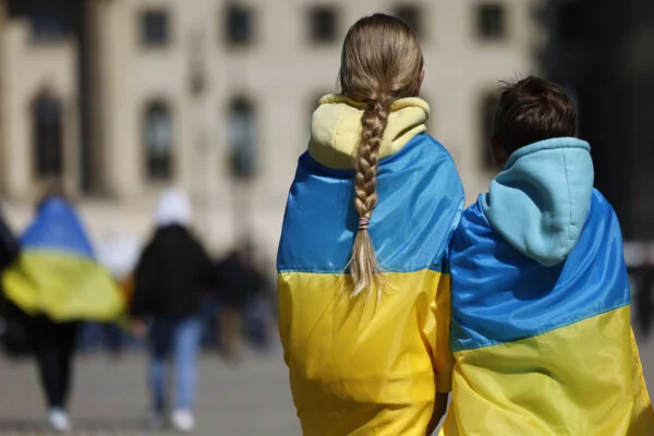 Двоє підлітків, загорнуті в український прапор, ідуть площею