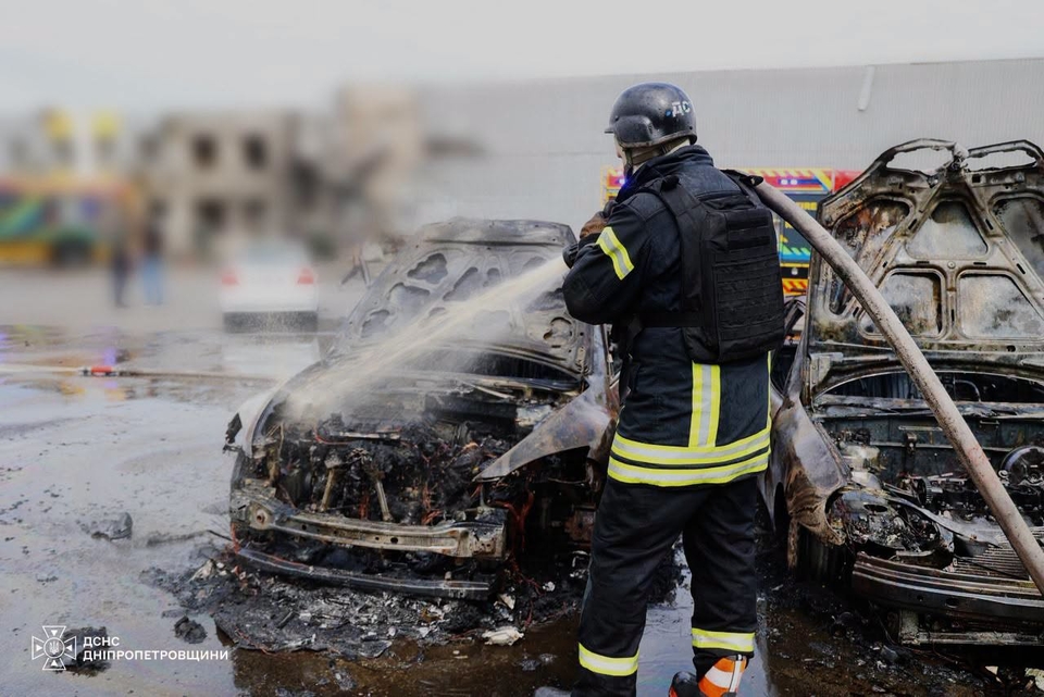 Рятувальник гасить згорілі автомобілі поблизу місця удару