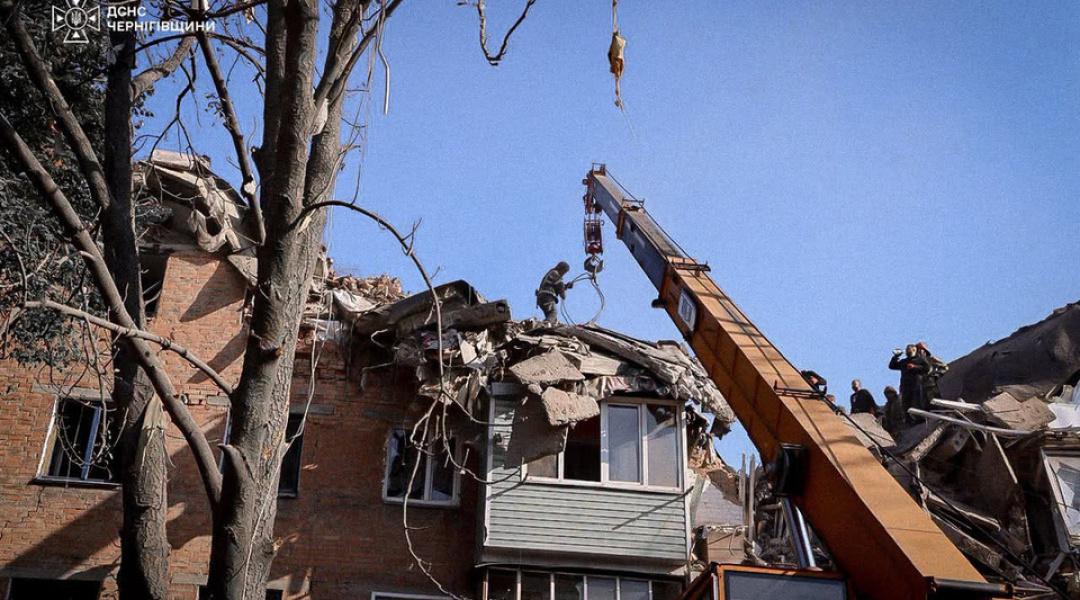 A mobile crane clears the rubble of the destroyed building in Pryluky