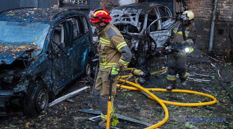 Rescuers working beside burnt-out cars in a residential courtyard