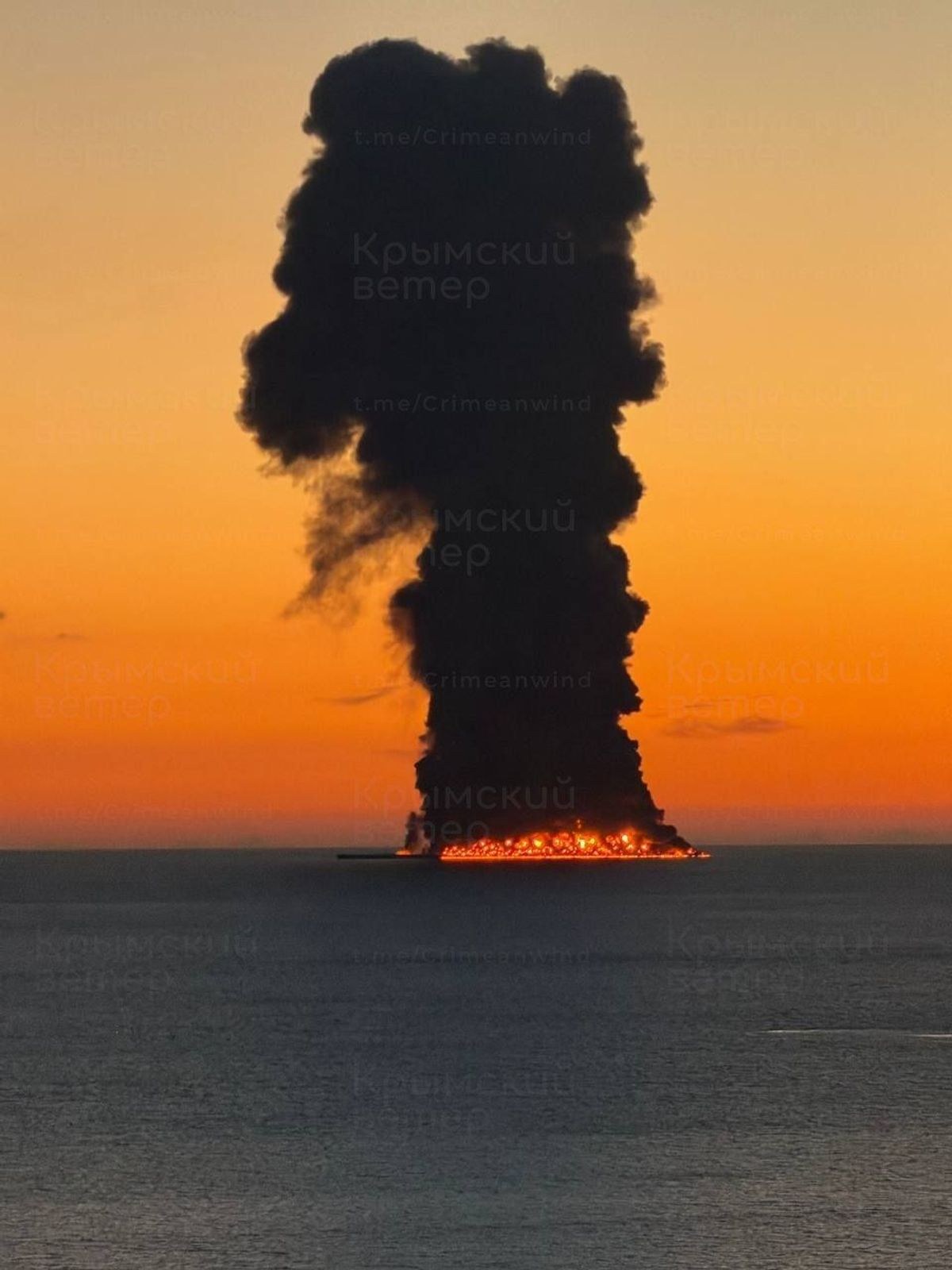 A column of smoke over the sea in the evening sky off Sochi