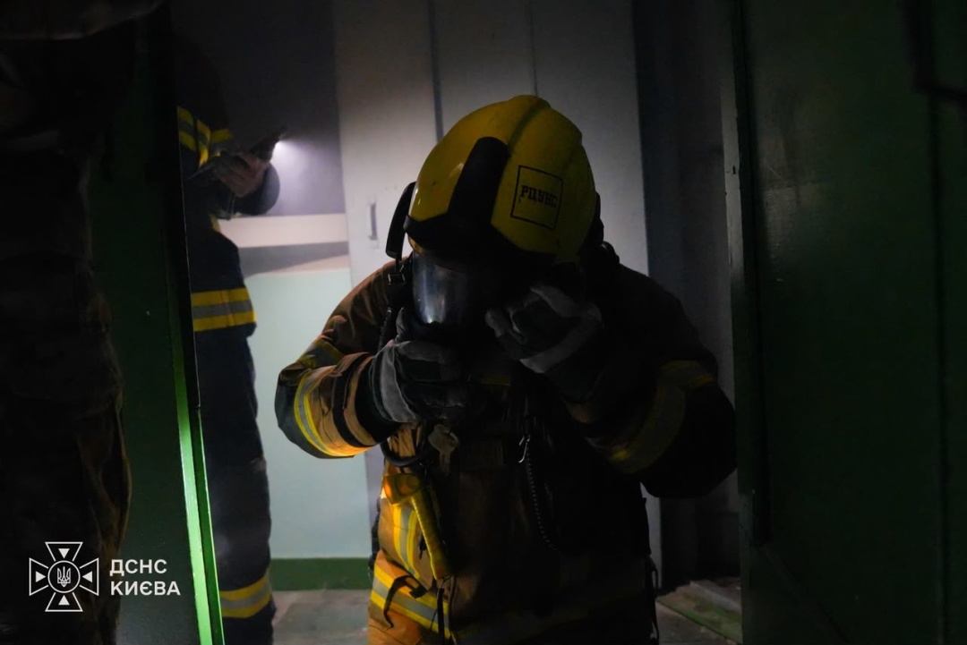 A rescuer in a protective mask works in a smoke-filled stairwell