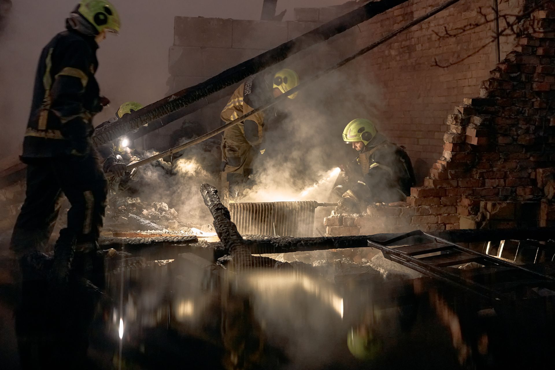 Helmeted rescuers search smoking rubble at night in Kyiv's Sviatoshynskyi district. Photo: Kyiv Independent / Getty
