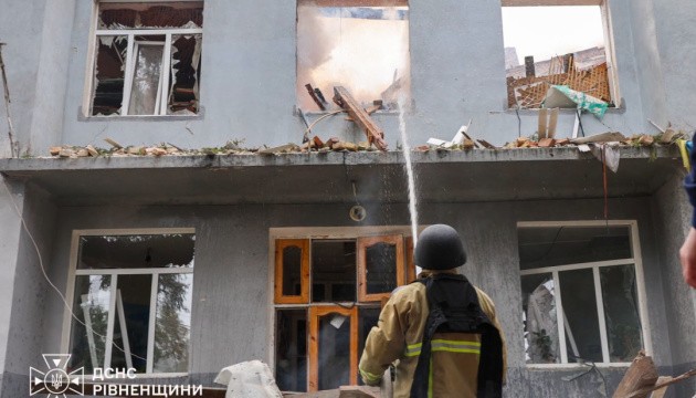 Пожежник гасить вогонь на фасаді пошкодженої будівлі