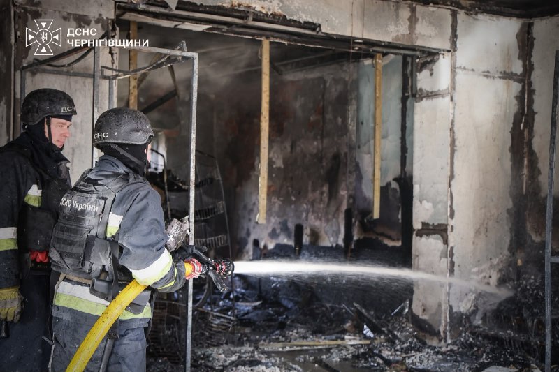 Rescuers putting out a fire inside a burnt-out shop